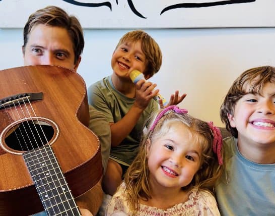 Rodrigo with guitar and the three kids, one on the toy mic