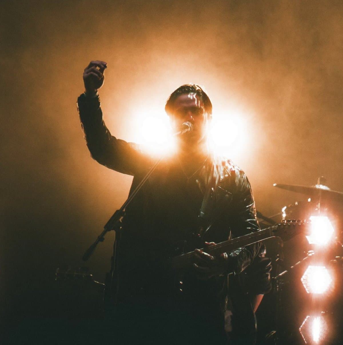 Backlit in amber smoke, fist raised